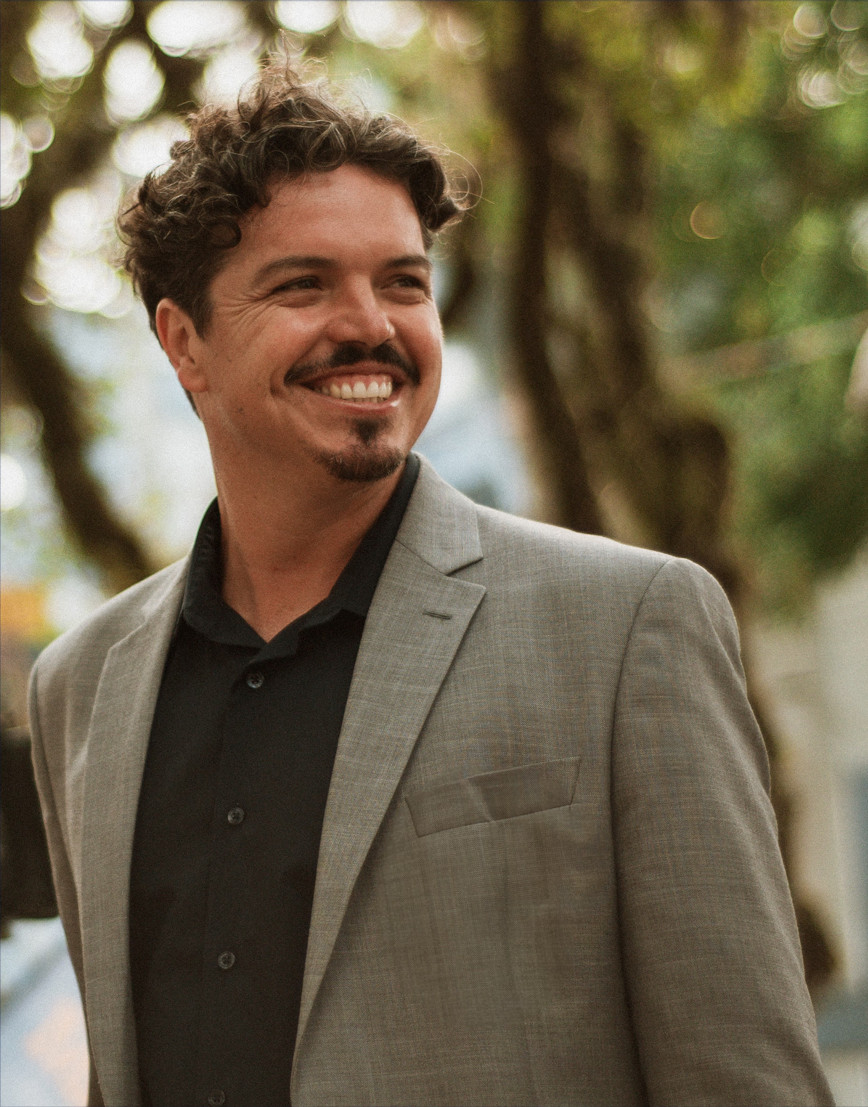 Marquito de paletó bege olhando levemente para seu lado esquerdo e sorrindo