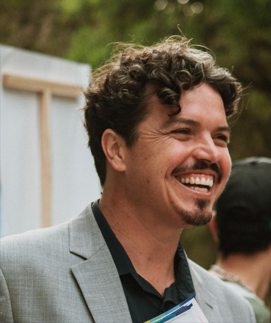 Marquito de paletó bege olhando levemente para frente e sorrindo