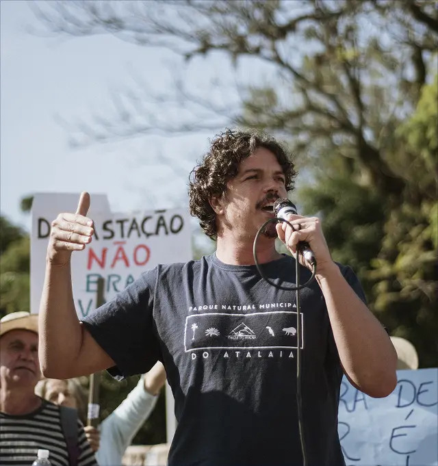 Marquito de paletó bege olhando levemente para frente e sorrindo